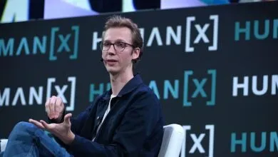 Andrej Karpathy speaking at the HumanX conference, gesturing while seated on stage.