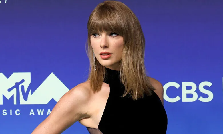 Taylor Swift posing on the red carpet at the MTV Video Music Awards in a black dress.