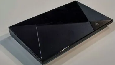 Black angular gaming console with geometric design resting on a light surface.