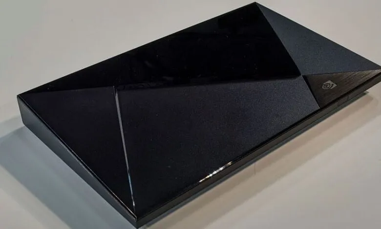 Black angular gaming console with geometric design resting on a light surface.