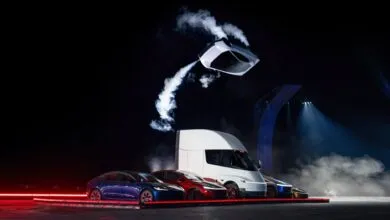 Tesla vehicles displayed on stage including a floating Cybercab surrounded by smoke.