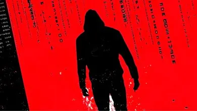 A silhouette of a hooded figure stands against a vibrant red background with cascading digital code.
