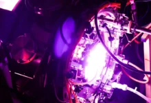 Complex scientific fusion reactor chamber glowing with intense purple and white light and tangled cables