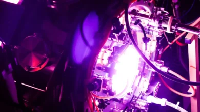 Complex scientific fusion reactor chamber glowing with intense purple and white light and tangled cables