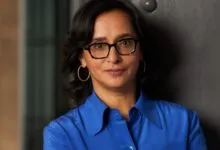 Portrait of Linda Yaccarino smiling gently in a vibrant blue collared shirt.