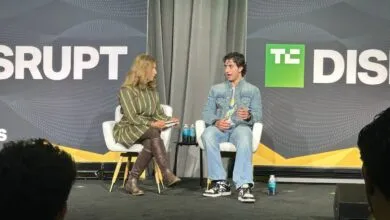 Two people sitting in white armchairs on stage at a TechCrunch Disrupt conference panel discussion.