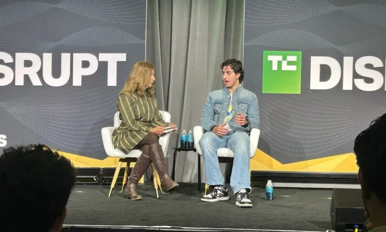 Two people sitting in white armchairs on stage at a TechCrunch Disrupt conference panel discussion.