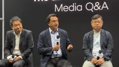 Three business executives speaking at a Hyundai Media Q&A panel discussion on stage.