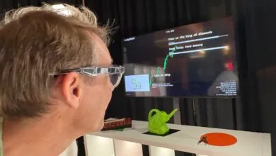 A person wearing smart glasses looks at a monitor displaying data and interactive prompts.