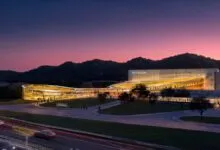 Futuristic Infinity One building glowing warmly at dusk against a rolling mountain backdrop.