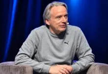 Software engineer Linus Torvalds wearing a gray Puma sweatshirt while speaking on stage.