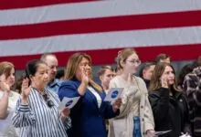 Diverse group of NASA employees raising their right hands to take an oath in front of an American flag.