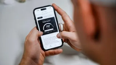 Close-up of hands holding a smartphone displaying the NTangible app with a Clutch Factor score of 717.