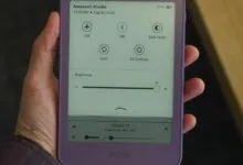 A person holding a purple Amazon Kindle e-reader displaying quick settings and brightness controls.