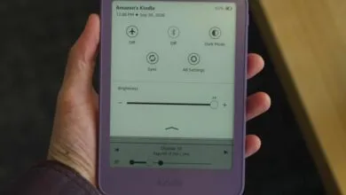 A person holding a purple Amazon Kindle e-reader displaying quick settings and brightness controls.