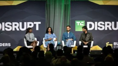 Four panelists seated in white armchairs on a stage at the TechCrunch Disrupt conference.