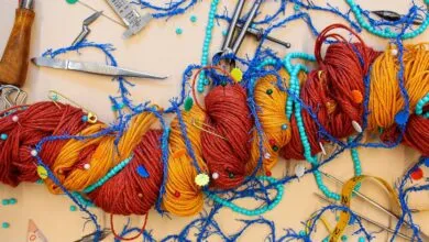 Colorful yarn, beads, and scientific instruments arranged on a neutral surface.