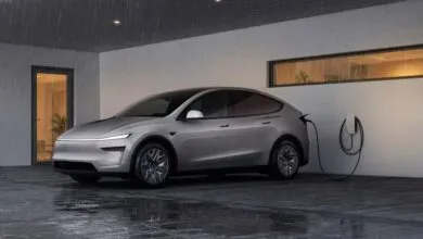 Silver Tesla electric vehicle charging in a modern carport during heavy rain