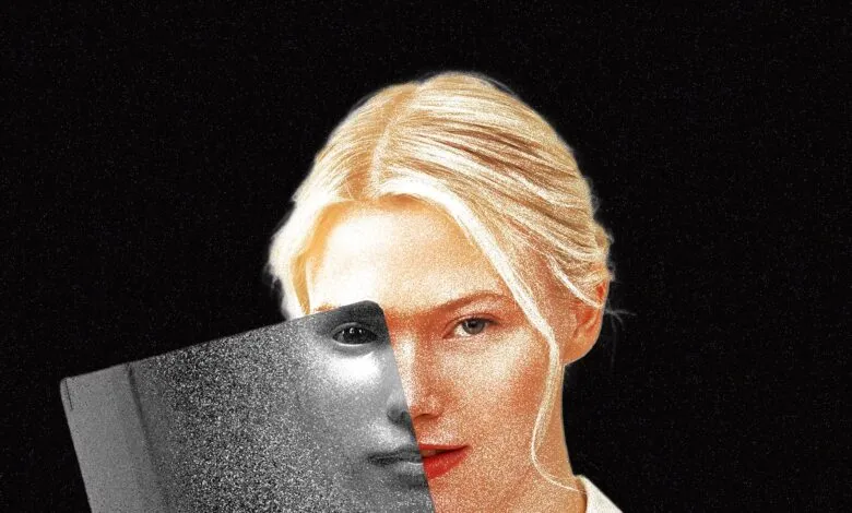 A blonde woman holding a glossy magazine partially over her face against a black textured background.
