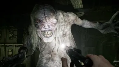 A terrifying mutated creature with sharp teeth illuminated by a flashlight in a dark basement.