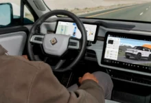 Driver seated inside a Rivian electric vehicle with hands off the steering wheel on a sunny highway