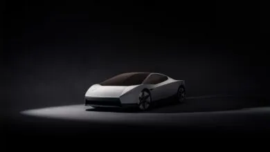 Sleek white futuristic sports car illuminated in a dark studio setting.