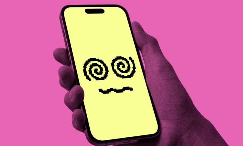 Hand holding a smartphone displaying a dizzy pixel face against a pink background.