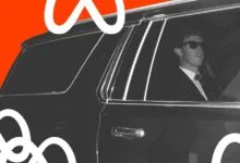 Meta CEO Mark Zuckerberg wearing sunglasses sits inside a black SUV against a vibrant orange backdrop.