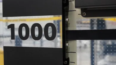 Close-up of a black metal panel featuring the number 1000 in bold digits and precision mechanical parts