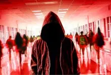 A hooded figure stands in the center of a crowded, red-tinted school hallway with blurred students.