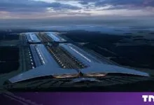 Aerial view of a massive futuristic industrial facility at dusk with glowing lights.