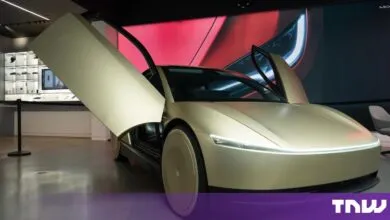 Gold Tesla Cybercab autonomous vehicle on display with its butterfly doors wide open in a showroom.