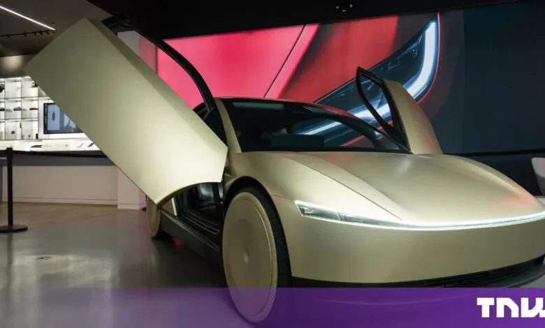 Gold Tesla Cybercab autonomous vehicle on display with its butterfly doors wide open in a showroom.