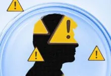 Silhouette of a head filled with yellow warning signs inside a petri dish against a light blue background.