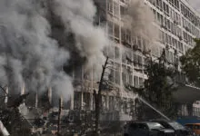 Thick white smoke billows from a damaged multi-story office building in Kyiv after an aerial drone strike.