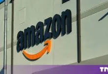The black Amazon logo and orange smile arrow mounted on a large grey warehouse wall.