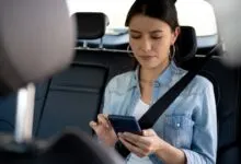Woman in backseat of car looking at smartphone with a feeling of motion sickness