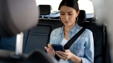 Woman in backseat of car looking at smartphone with a feeling of motion sickness