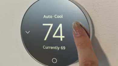 A finger adjusting a round smart thermostat displaying Auto Cool at 74 degrees