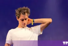 Arthur Mensch, CEO of Mistral AI, touches his neck while speaking on stage at a conference.