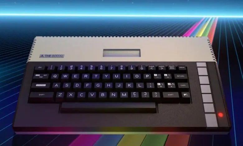 An Atari 800XL computer sits on a reflective surface against a retro futuristic neon grid background.