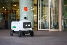 Avride autonomous delivery robot with Uber Eats branding parked outside a modern building.
