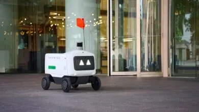 Avride autonomous delivery robot with Uber Eats branding parked outside a modern building.