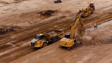 Aerial view of yellow Caterpillar excavator loading dirt into a dump truck at a construction site
