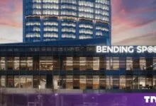 Modern Bending Spoons corporate headquarters building illuminated at dusk with a colorful sky.