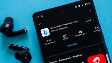Smartphone displaying the Microsoft Bing Webmaster Tools app next to black wireless earbuds on a blue background