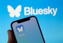 Smartphone displaying the Bluesky social media app with its butterfly logo against a blue background.