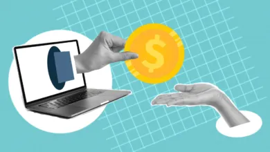 A grayscale hand reaches from a laptop screen to pass a large yellow dollar coin to an open hand below.