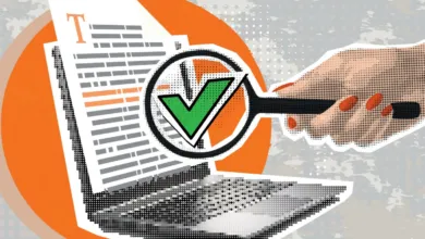 A hand holds a magnifying glass over a document on a laptop, revealing a green checkmark.
