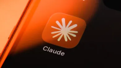 Close-up of a smartphone screen showing the Claude AI app icon with warm orange backlighting
